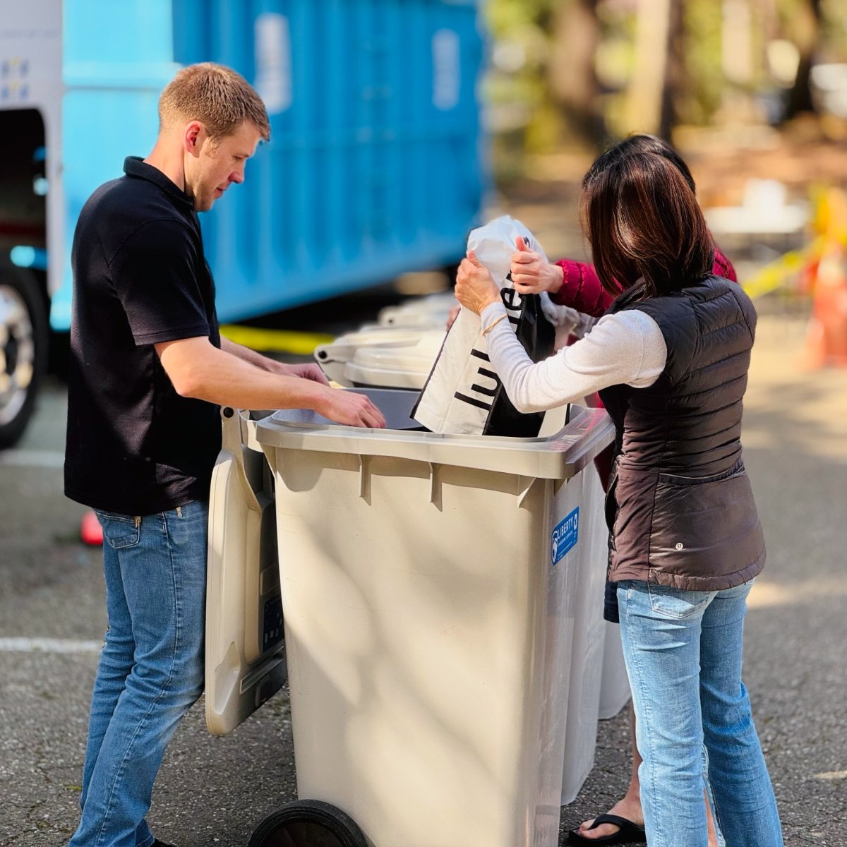 man helps women put documents into a shredding bin