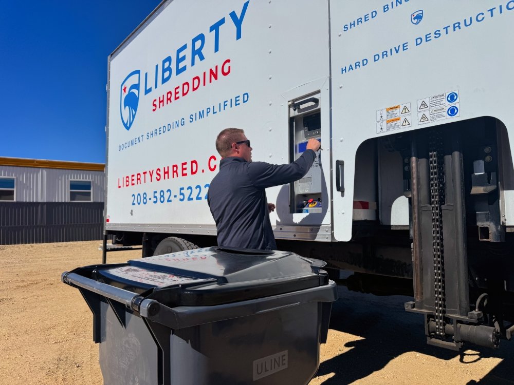 Liberty team member operating a mobile shredding truck beside paper collection bins